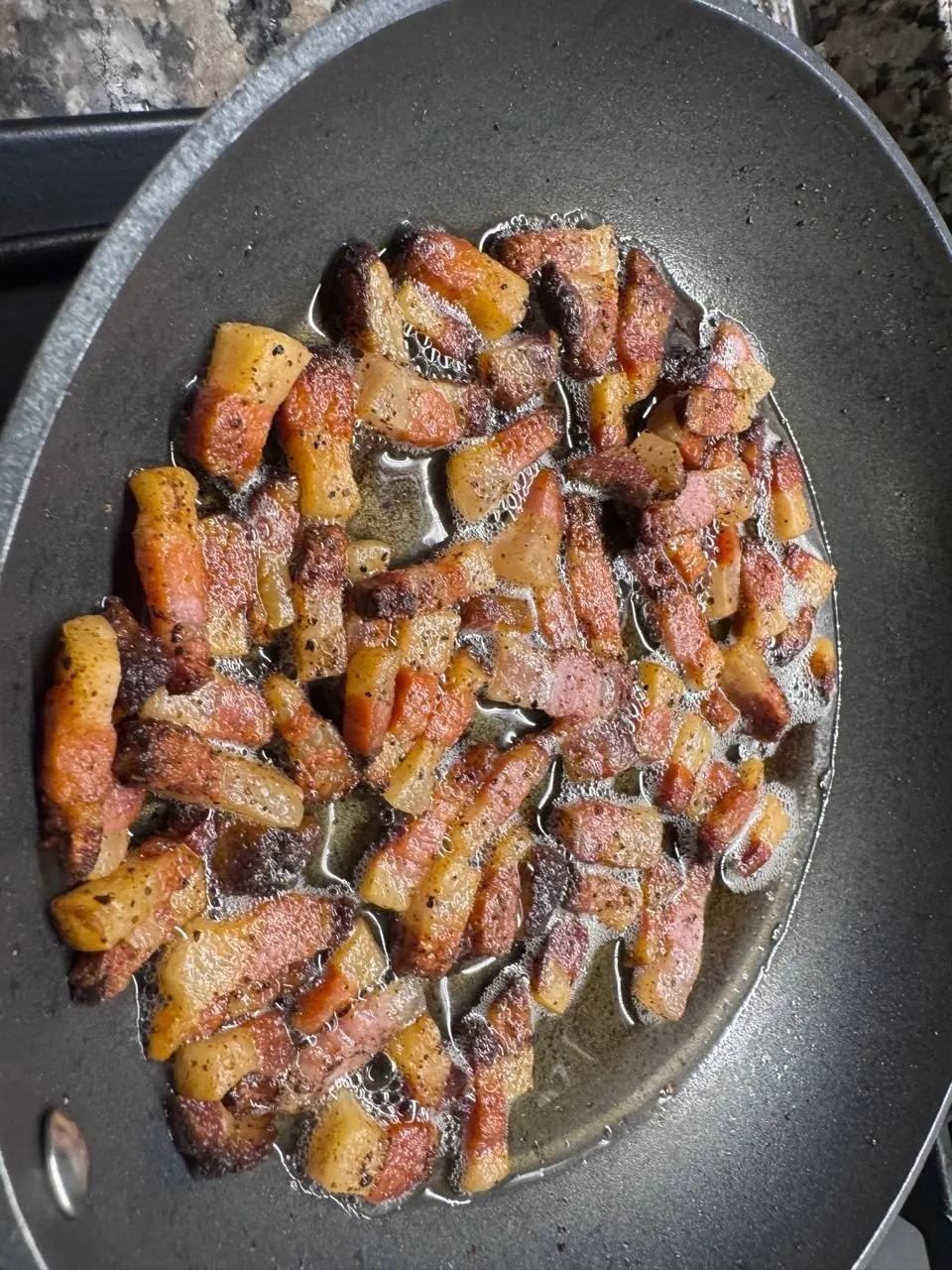 Guanciale dorado en la sartén, con la grasa derretida alrededor